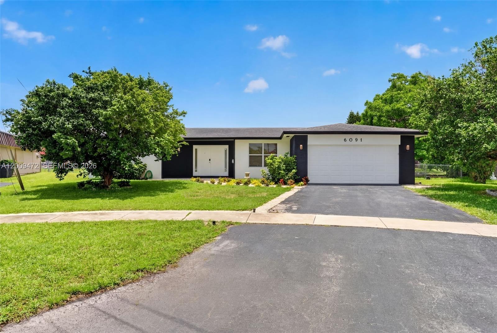 A single-story house with a white and black exterior, a two-car garage, and a driveway — 6091 SW 14th St, Plantation FL 33317, PLANTATION, FL