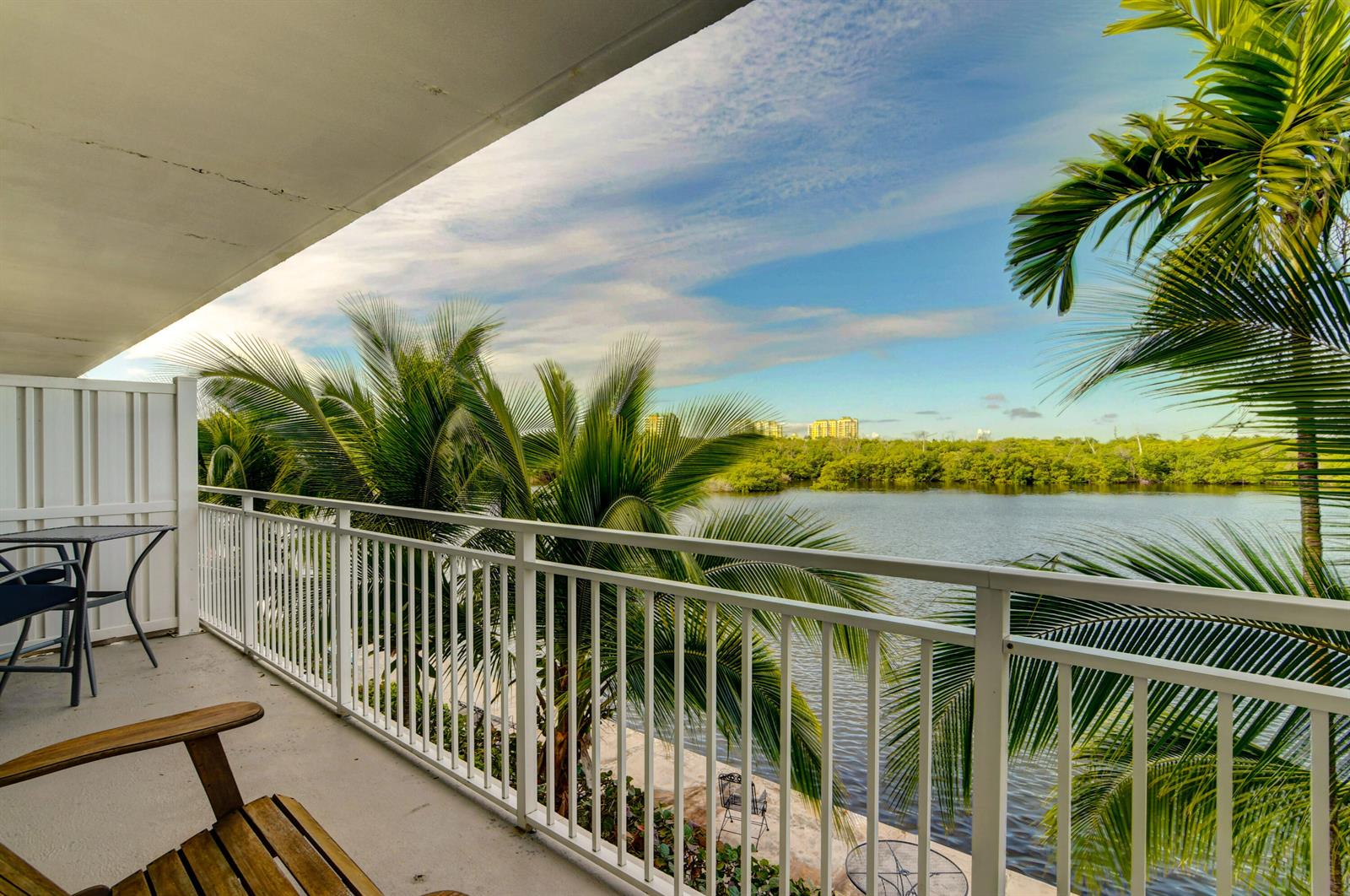 A balcony with a white railing overlooks a body of water and palm trees — 6520 N Ocean Boulevard # 24, Ocean Ridge FL 33435, OCEAN RIDGE, FL