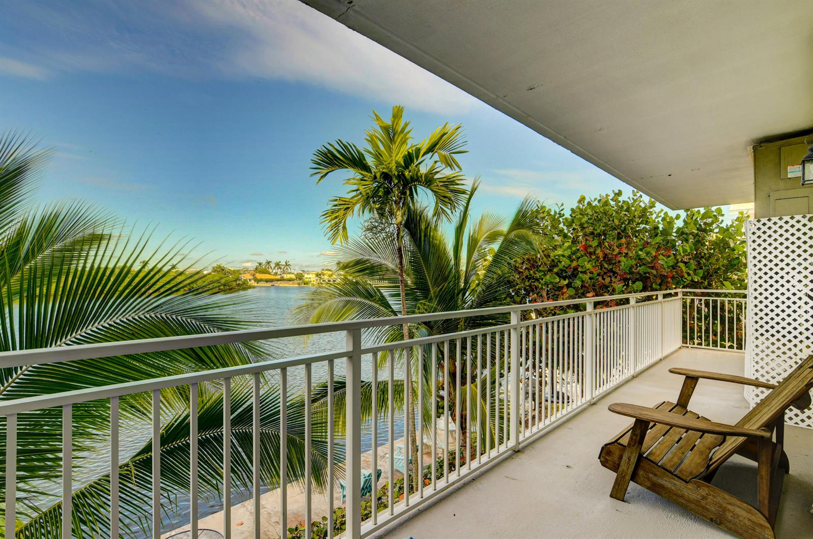A balcony with a white railing overlooks a body of water and palm trees — 6520 N Ocean Boulevard # 24, Ocean Ridge FL 33435, OCEAN RIDGE, FL