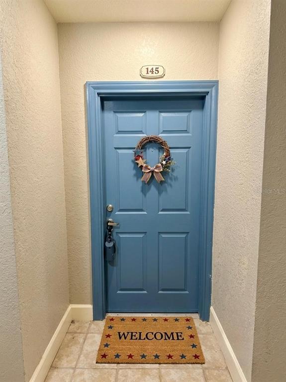 A blue front door with a wreath and a welcome mat is numbered 145 — 860 N ORANGE AVENUE UNIT 145, ORLANDO, FL