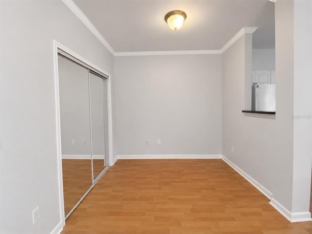 An empty room with light gray walls, wood-look flooring, and mirrored sliding closet doors — 860 N ORANGE AVENUE UNIT 145, ORLANDO, FL