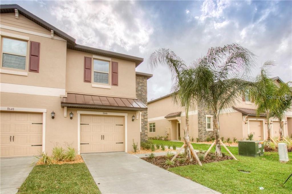A two-story tan townhouse with a two-car garage and a small palm tree outside — 11646 CASTINE STREET, NEW PORT RICHEY, FL