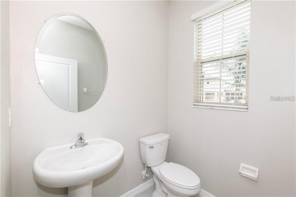 A half bathroom features a pedestal sink, an oval mirror, and a toilet — 11646 CASTINE STREET, NEW PORT RICHEY, FL