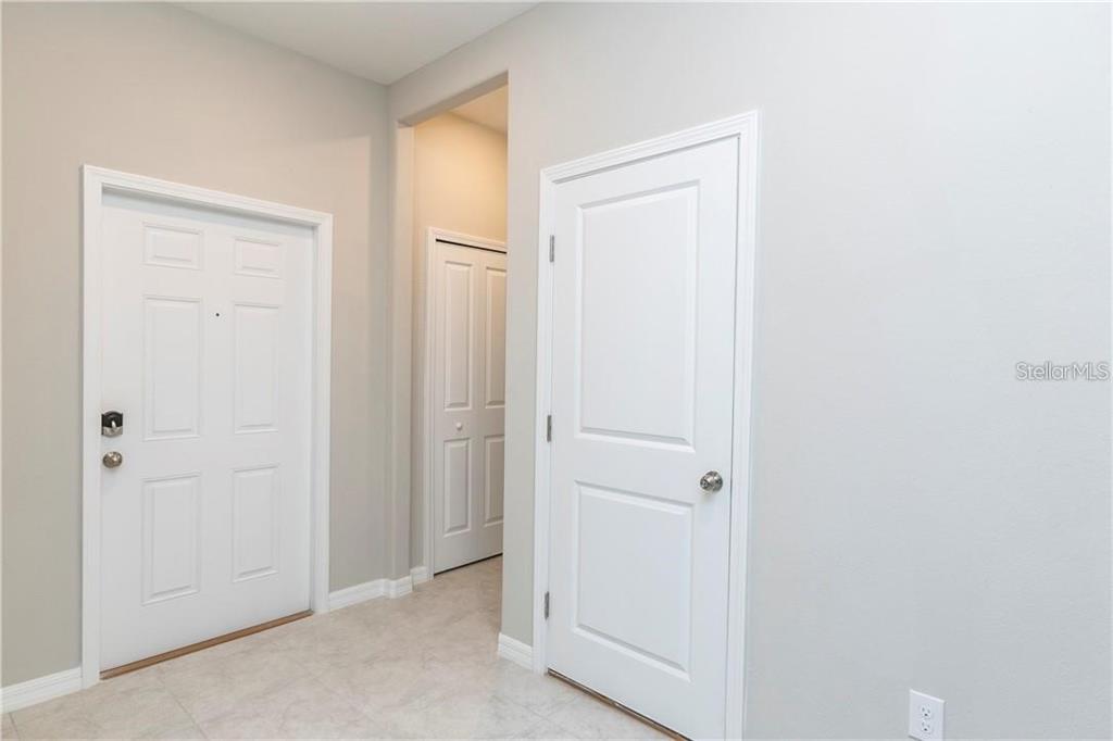 An interior view shows a hallway with three white doors and light-colored tile flooring — 11646 CASTINE STREET, NEW PORT RICHEY, FL