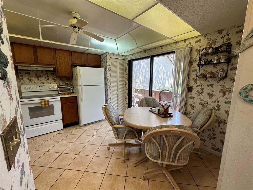 A kitchen and dining area features floral wallpaper, tile flooring, and a sliding glass door — 1647 BROOKHOUSE COURT UNIT 246, SARASOTA, FL