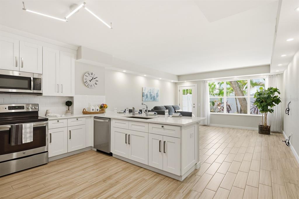 A modern kitchen with white cabinets and an island opens into a bright living area — 4811 BAYSHORE BOULEVARD UNIT 303, TAMPA, FL