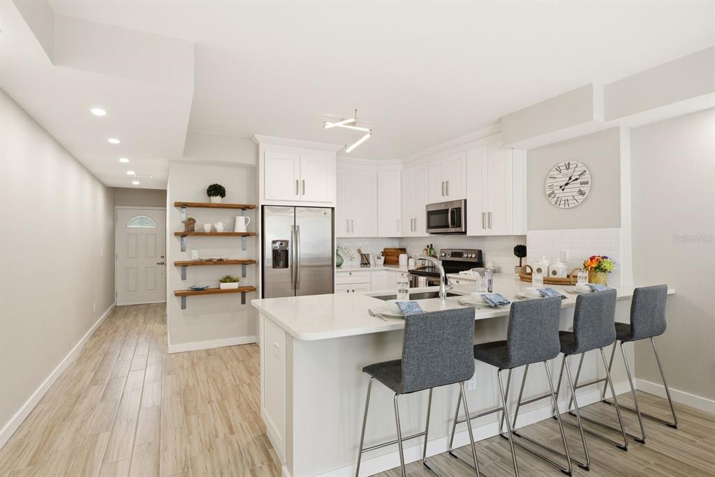A modern kitchen features white cabinetry, stainless steel appliances, a quartz island, and bar seating — 4811 BAYSHORE BOULEVARD UNIT 303, TAMPA, FL