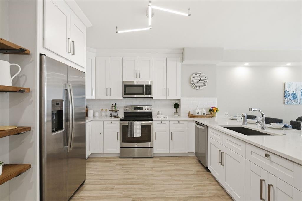 A modern kitchen features white cabinetry, stainless steel appliances, and light wood-look tile flooring — 4811 BAYSHORE BOULEVARD UNIT 303, TAMPA, FL