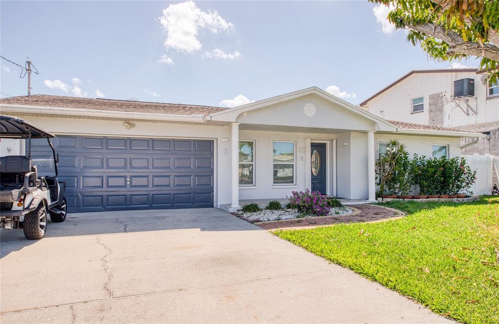 A single-story house with a gray garage, white exterior, and a golf cart in the driveway — 551 CRYSTAL DRIVE, MADEIRA BEACH, FL