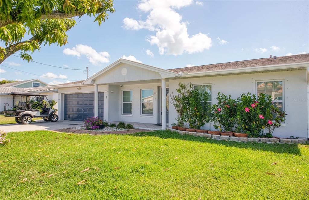A single-story house with a white stucco exterior, a garage, and a golf cart parked outside — 551 CRYSTAL DRIVE, MADEIRA BEACH, FL