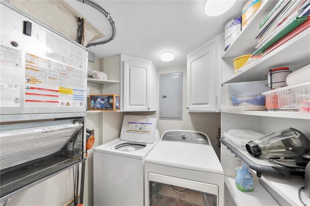 A laundry room features a top-load washer, front-load dryer, white cabinets, and open shelving — 4445 S ATLANTIC AVENUE UNIT 202, PONCE INLET, FL