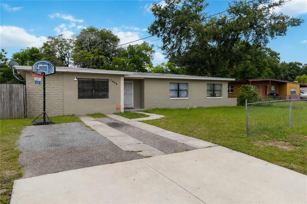 A single-story tan house with a concrete driveway and a basketball hoop in the front yard — 1408 ROGER BABSON ROAD, ORLANDO, FL
