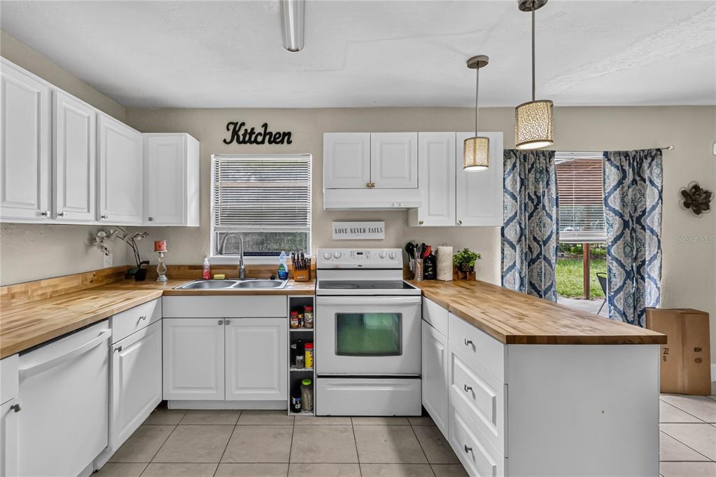 A kitchen features white cabinets, butcher block countertops, a white range, and tile flooring — 1408 ROGER BABSON ROAD, ORLANDO, FL
