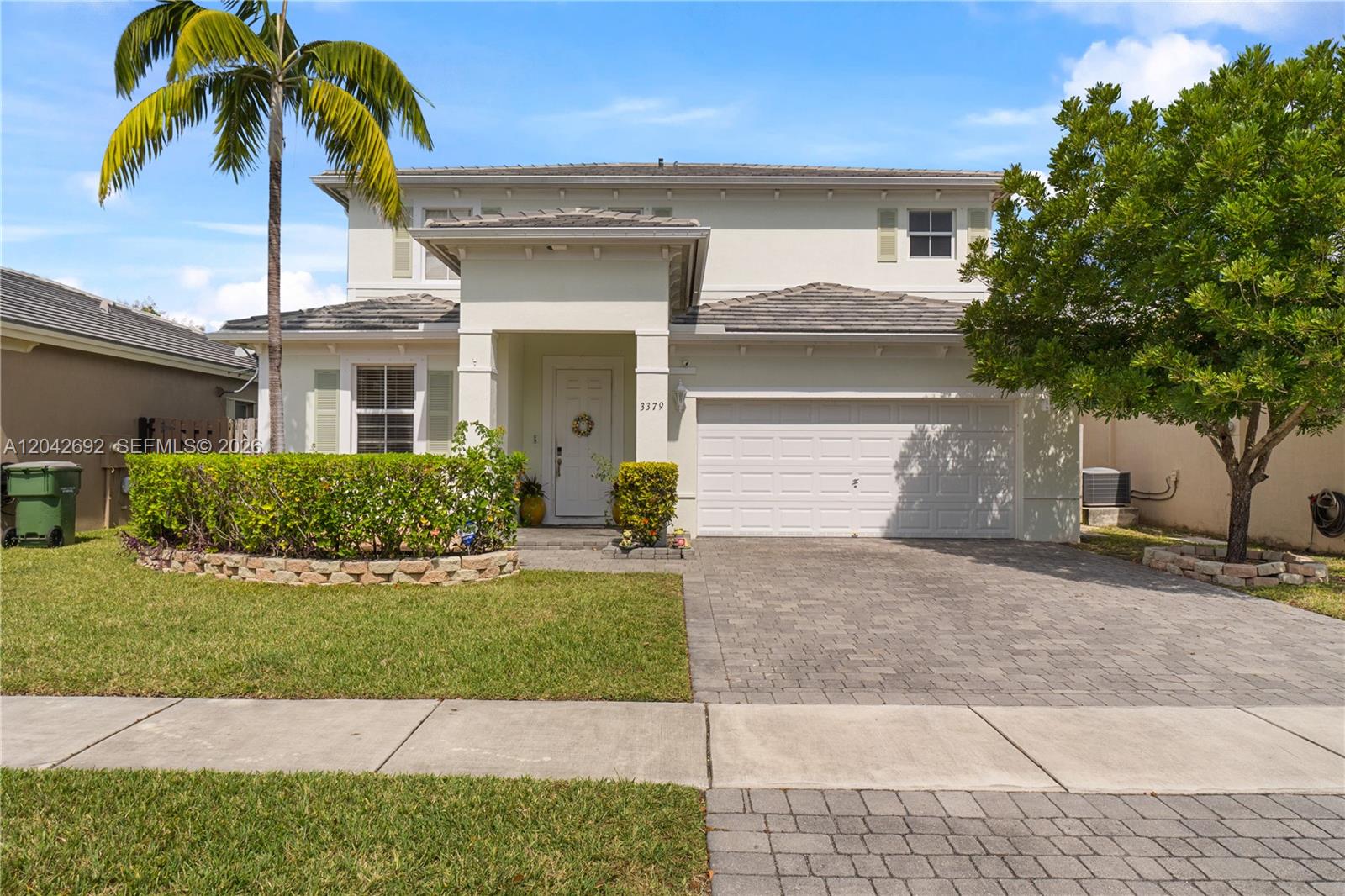 A two-story house with a paved driveway, a garage, and a palm tree in front — 3379 NE 1st St, Homestead FL 33033, HOMESTEAD, FL