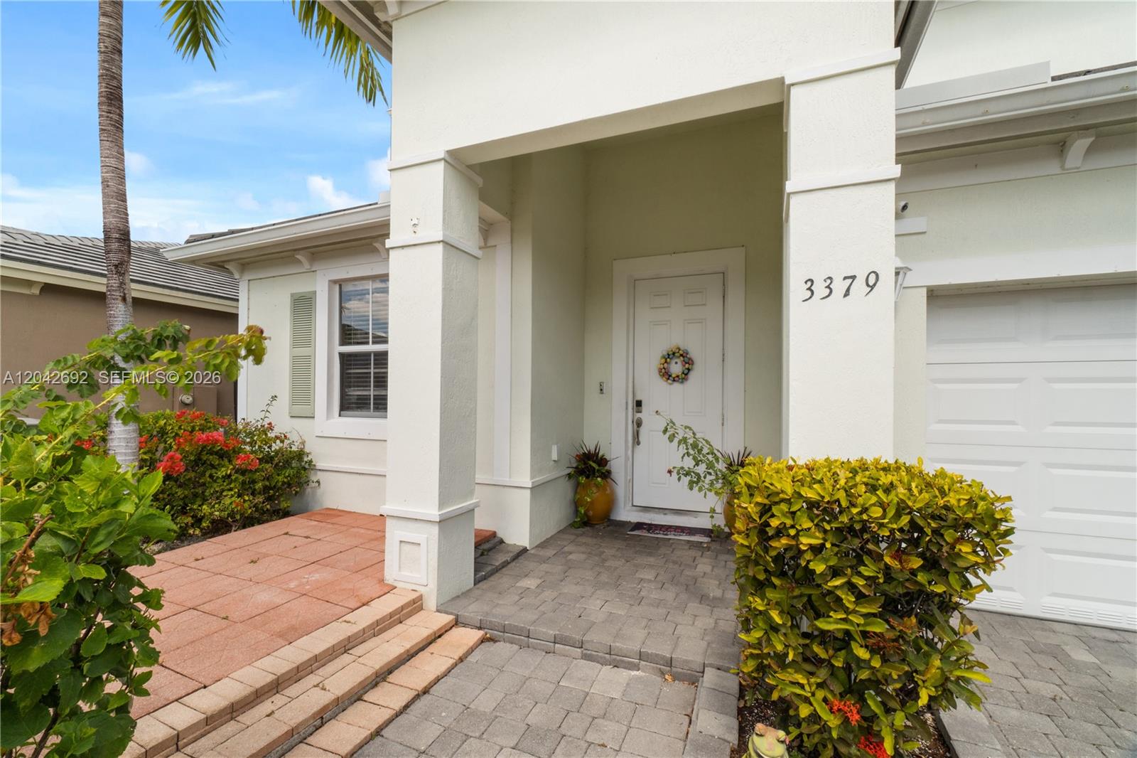 The exterior view shows a white house entrance with a paved walkway and landscaping — 3379 NE 1st St, Homestead FL 33033, HOMESTEAD, FL