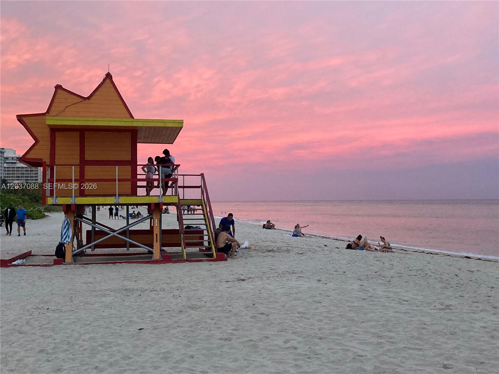 A colorful lifeguard tower stands on a sandy beach under a pink sunset sky — 2301 Collins Ave # 614, Miami Beach FL 33139, MIAMI BEACH, FL