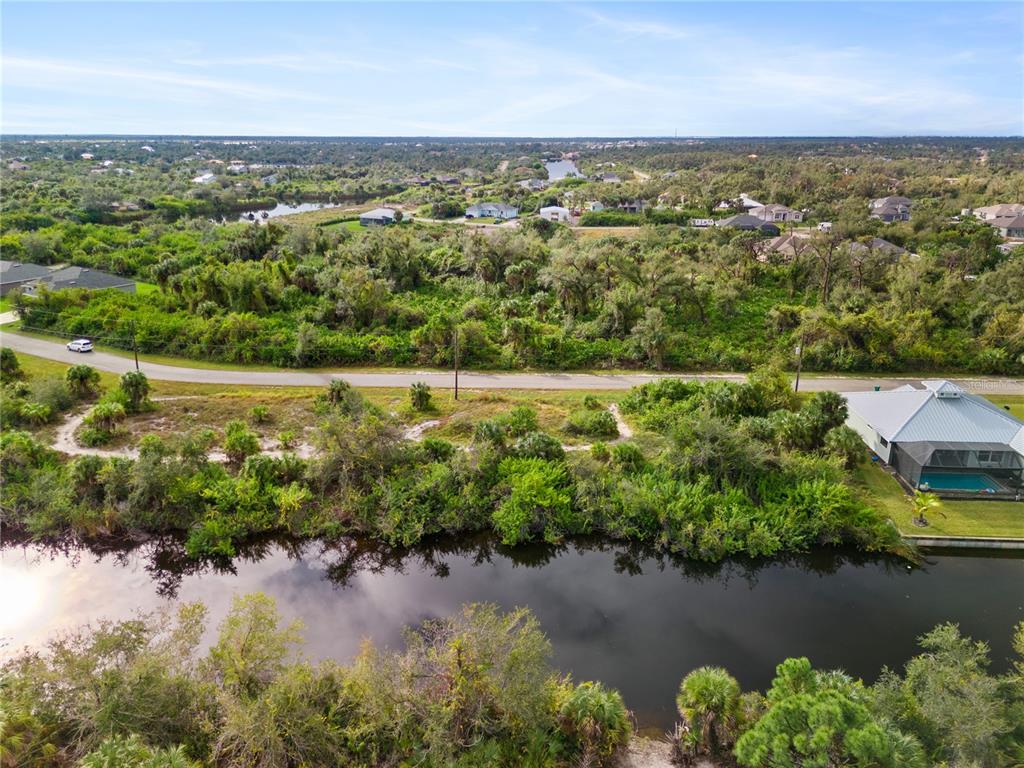 An aerial view shows a vacant lot situated between a canal and a paved road — 13228 AMARYLLIS CIRCLE, PORT CHARLOTTE, FL