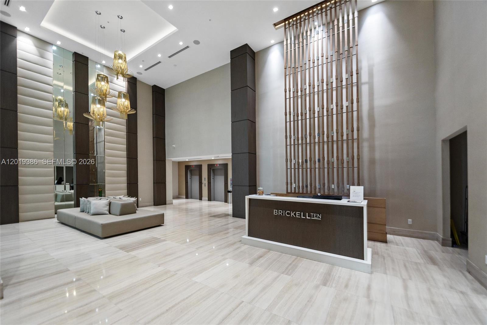 A modern building lobby features a reception desk, a lounge area, and tall decorative screens — 1010 SW 2nd Ave # 1709, Miami FL 33130, MIAMI, FL