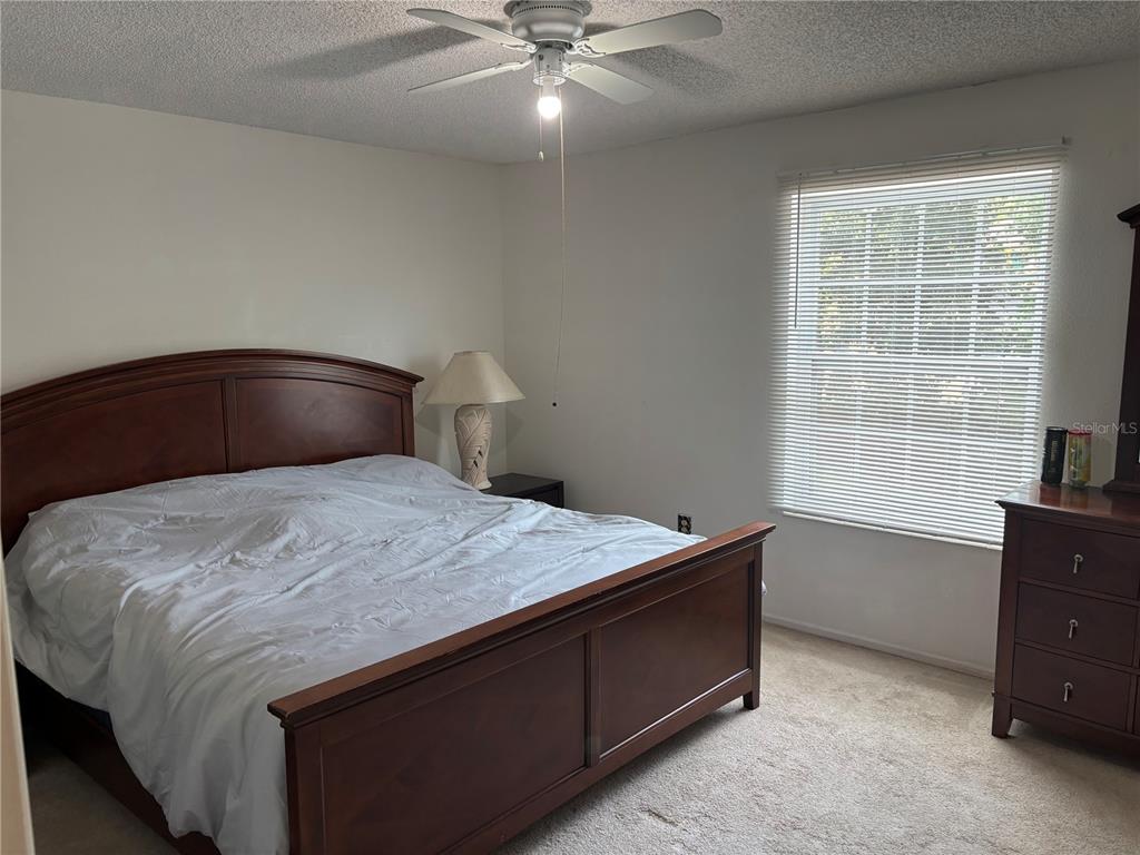 A bedroom features a wooden bed frame, a ceiling fan, and a window with blinds — 3425 41ST TERRACE S UNIT 203, ST PETERSBURG, FL