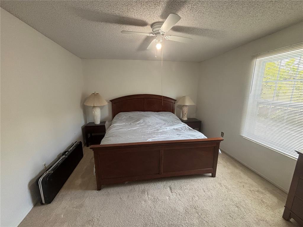 A bedroom features a wooden bed frame, two nightstands with lamps, and a ceiling fan — 3425 41ST TERRACE S UNIT 203, ST PETERSBURG, FL