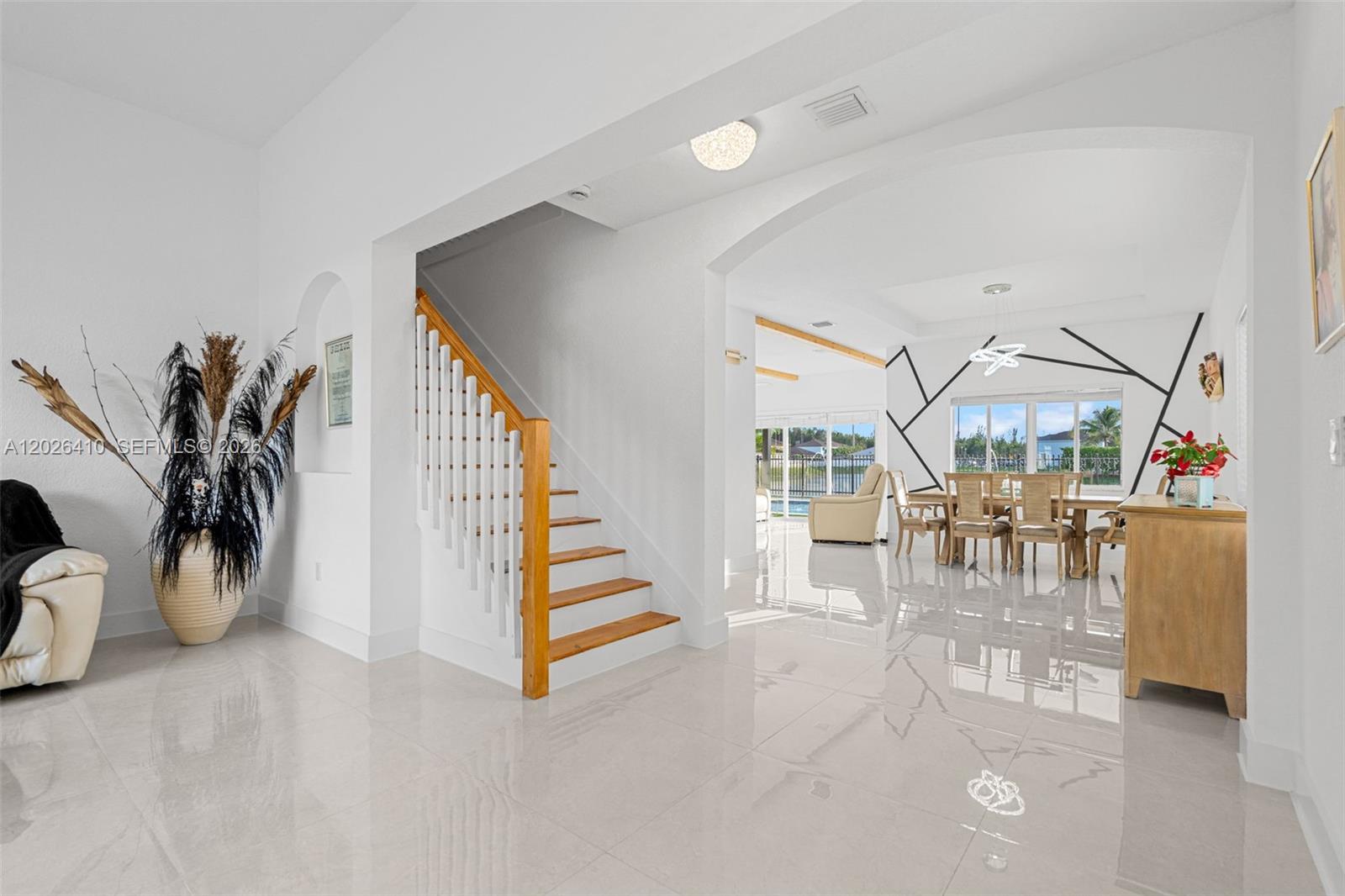 A bright foyer with white tile floors leads to a staircase and a dining area — 1680 SW 154th Path, Miami FL 33185, MIAMI, FL
