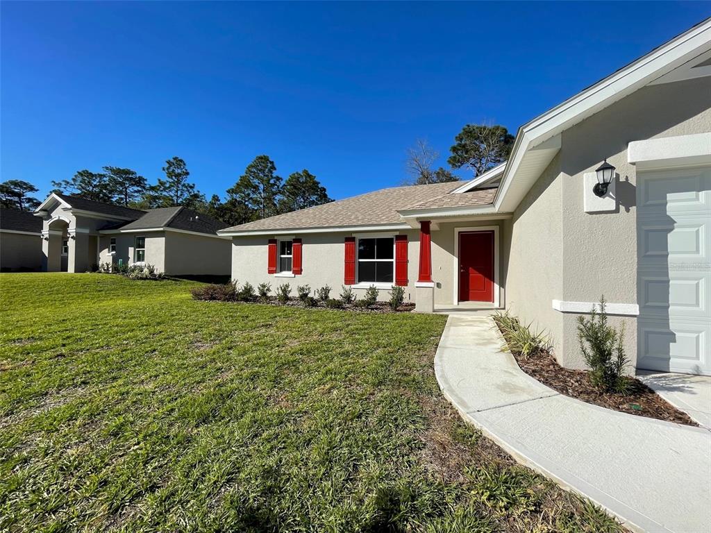 A single-story house with a red front door, red shutters, and a concrete walkway — 2377 W MENORES DRIVE, CITRUS SPRINGS, FL