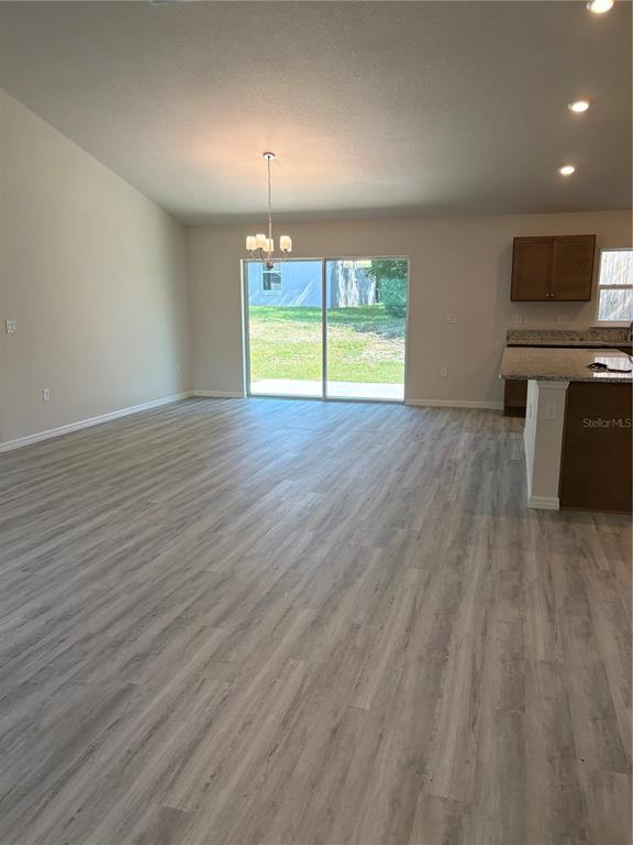 An open-concept living area features light wood-look flooring, a dining chandelier, and a sliding door — 2377 W MENORES DRIVE, CITRUS SPRINGS, FL