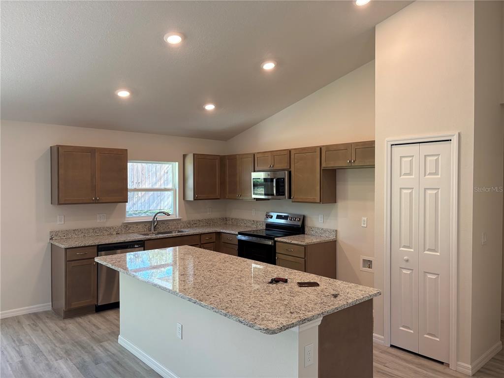 A kitchen features wood cabinets, granite countertops, a center island, and stainless steel appliances — 2377 W MENORES DRIVE, CITRUS SPRINGS, FL