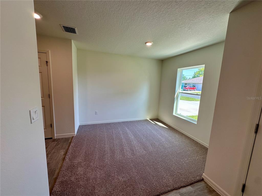 A carpeted room with light walls, a window, and a doorway leading to a hallway — 12 ROYAL LEAF LANE, PALM COAST, FL