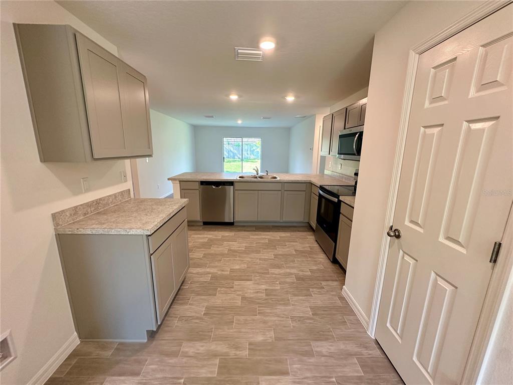 A kitchen features gray cabinets, stainless steel appliances, and light-colored tile flooring — 12 ROYAL LEAF LANE, PALM COAST, FL