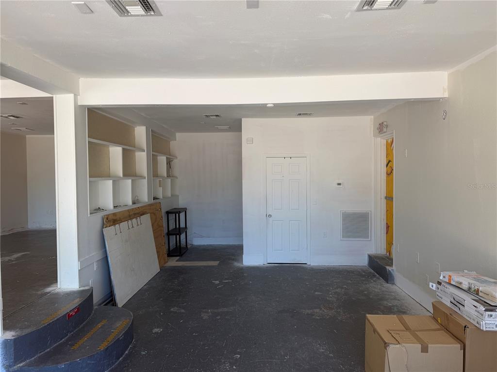An unfinished room features a white door, built-in shelving, and a concrete floor — 1771 CLEARWATER LARGO ROAD, CLEARWATER, FL