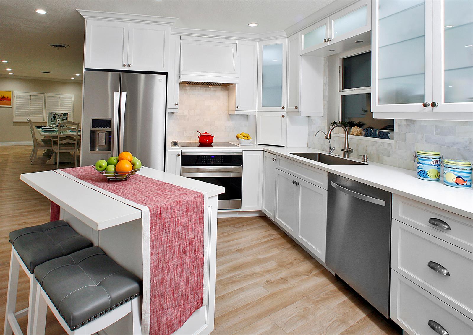 A white kitchen features stainless steel appliances, a center island, and light wood-look flooring — 5501 N Ocean Boulevard, Ocean Ridge FL 33435, OCEAN RIDGE, FL