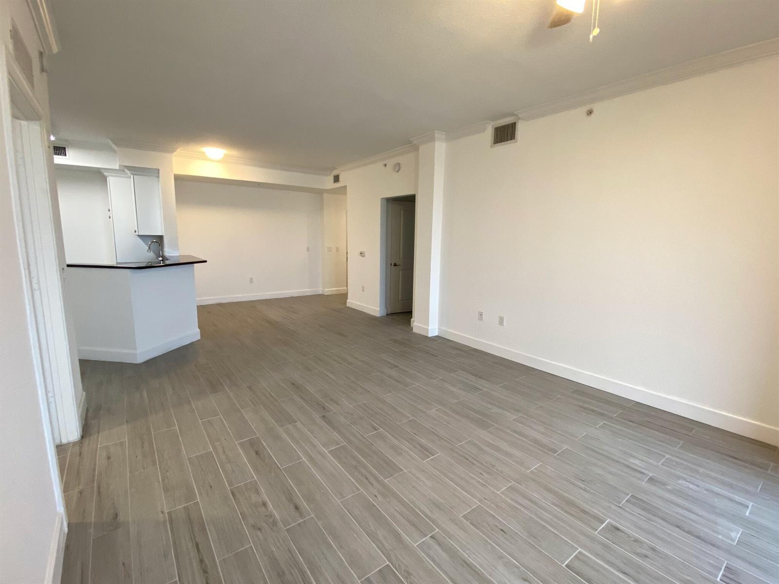 An open-concept living area features light wood-look tile flooring and a kitchen breakfast bar — 1690 Renaissance Commons Boulevard # 1418, Boynton Beach FL 33426, BOYNTON BEACH, FL