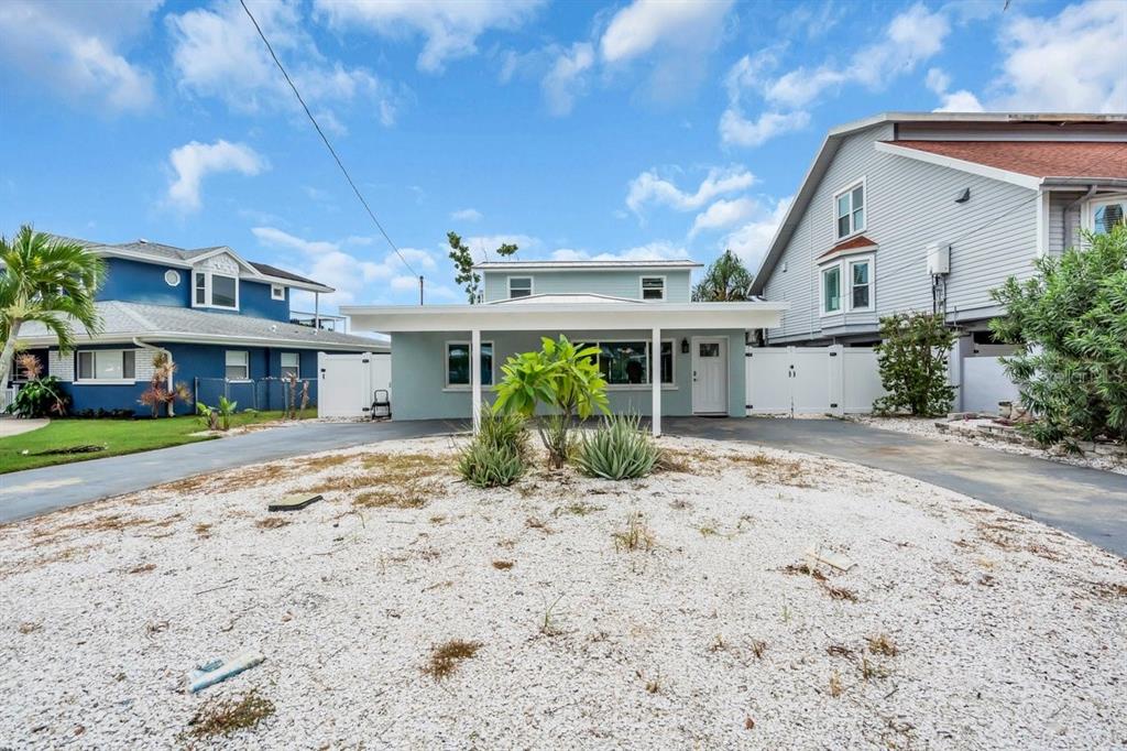 A light blue two-story house features a flat-roofed carport and a white gravel front yard — 349 BAHIA VISTA DRIVE, INDIAN ROCKS BEACH, FL