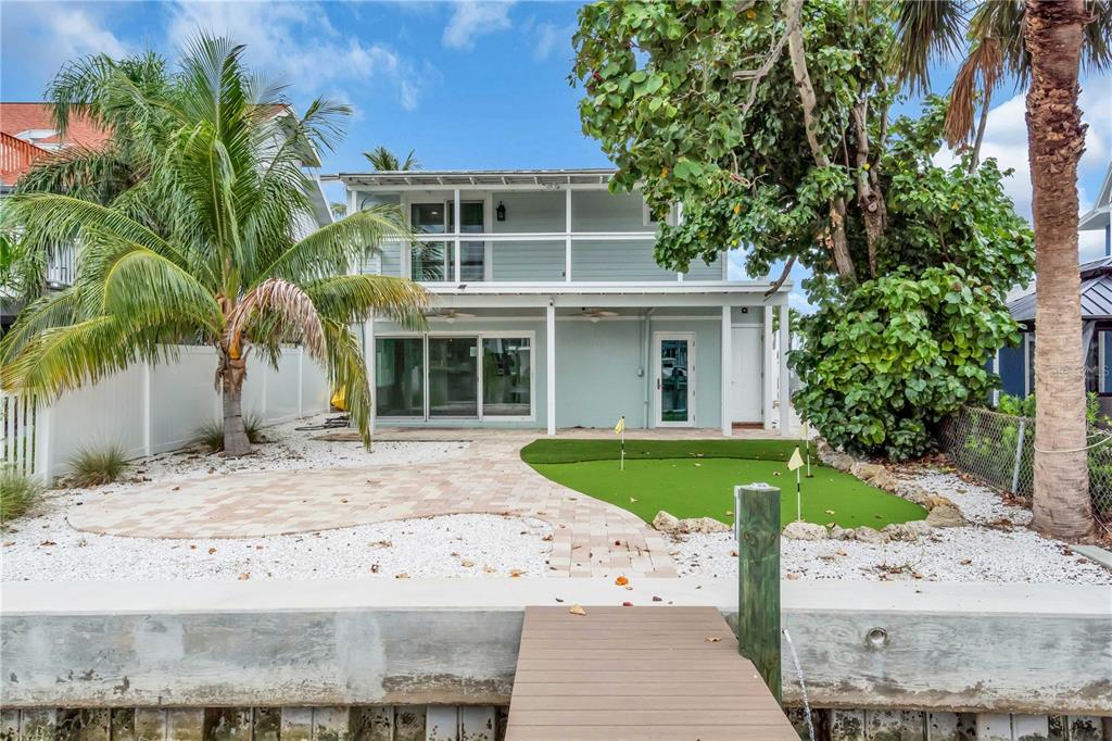 The exterior of a two-story house features a backyard putting green and a boat dock — 349 BAHIA VISTA DRIVE, INDIAN ROCKS BEACH, FL