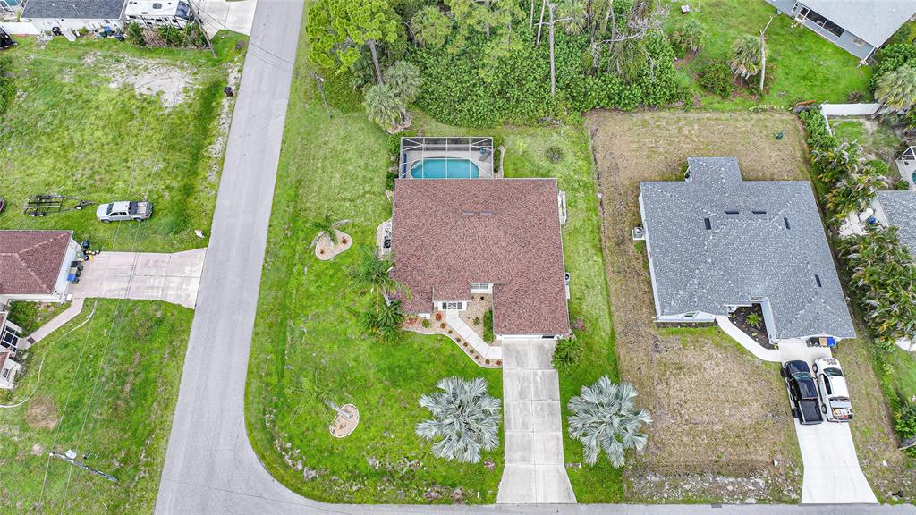 An aerial view shows a house with a pool, driveway, and surrounding lawn — 5379 ENSLEY TERRACE, NORTH PORT, FL