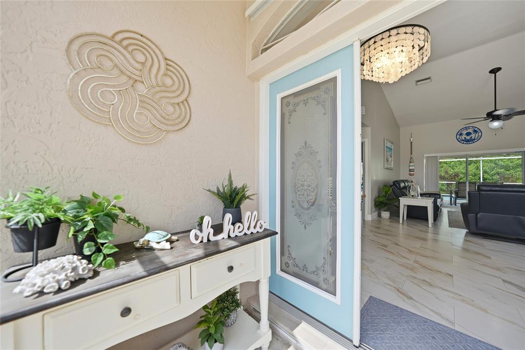 A light blue front door opens into a bright home with a white console table — 5379 ENSLEY TERRACE, NORTH PORT, FL