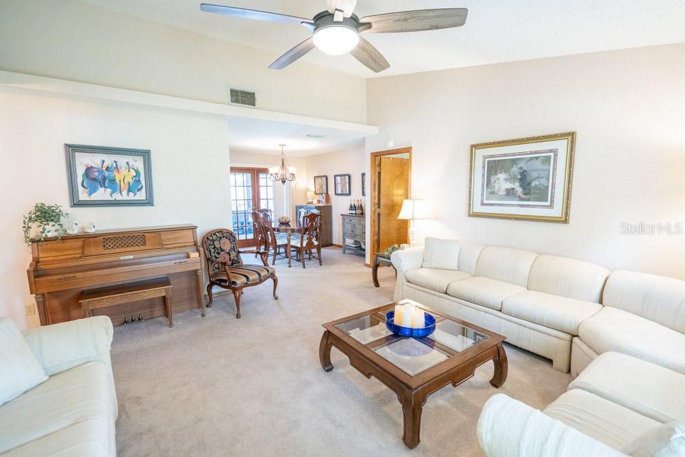 A living room features a white sectional sofa, a wooden coffee table, and an upright piano — 7213 REGENT DRIVE, LAKELAND, FL
