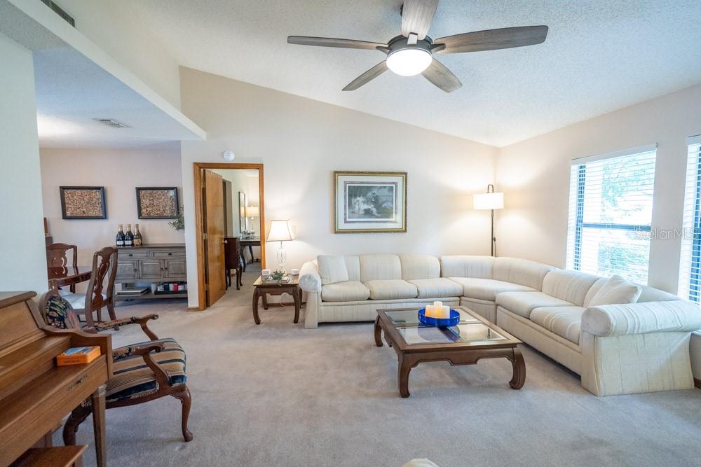 A living room features a large sectional sofa, a coffee table, and a ceiling fan — 7213 REGENT DRIVE, LAKELAND, FL