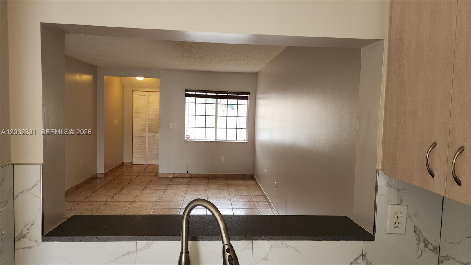 A kitchen pass-through window overlooks a tiled living area with a window and closet — 6416 SW 131st Path # 1705, Miami FL 33183, MIAMI, FL