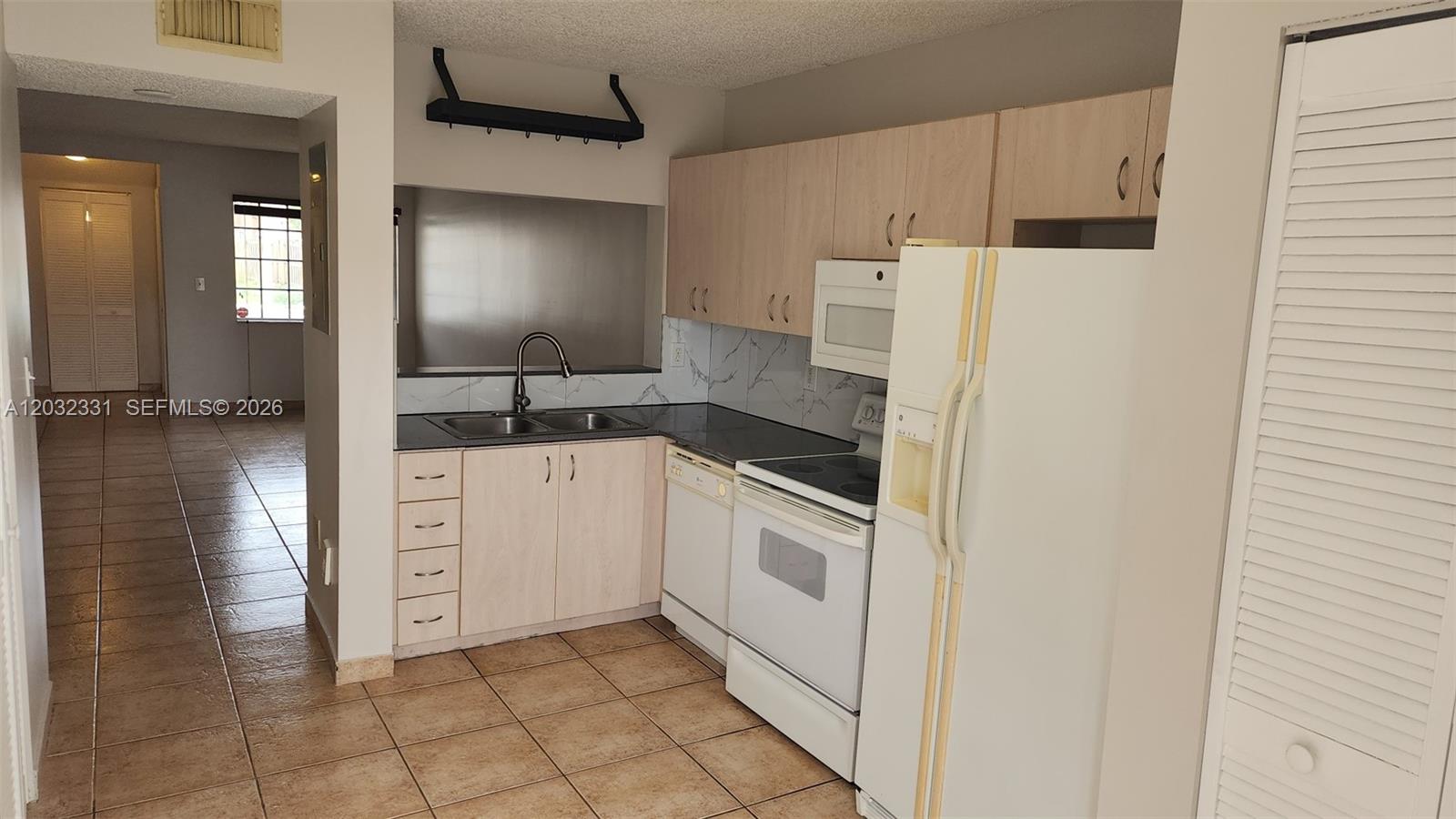 A kitchen features light wood cabinets, white appliances, a dark countertop, and tiled flooring — 6416 SW 131st Path # 1705, Miami FL 33183, MIAMI, FL