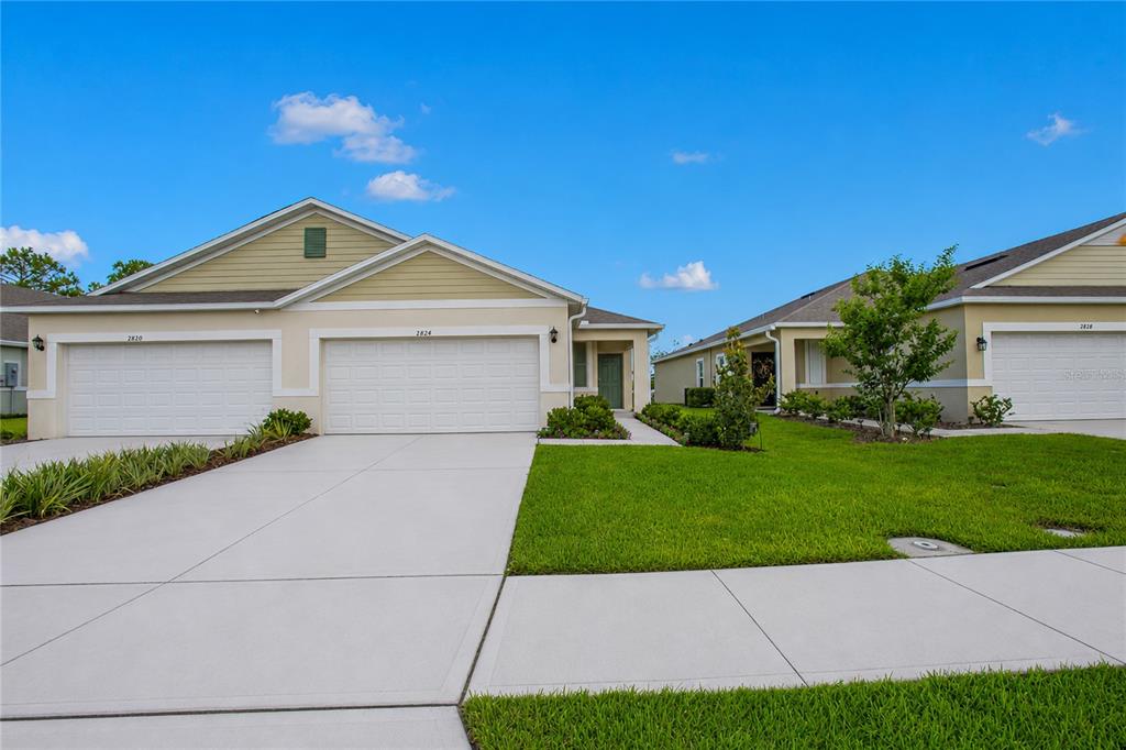 A single-story duplex with two white garage doors and a green front door — 2824 SUNRIDGE LOOP, ST CLOUD, FL