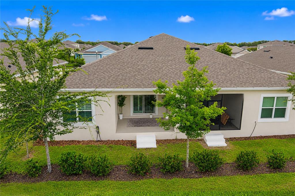 The rear exterior of a single-story house features a covered patio and a screened lanai — 2824 SUNRIDGE LOOP, ST CLOUD, FL