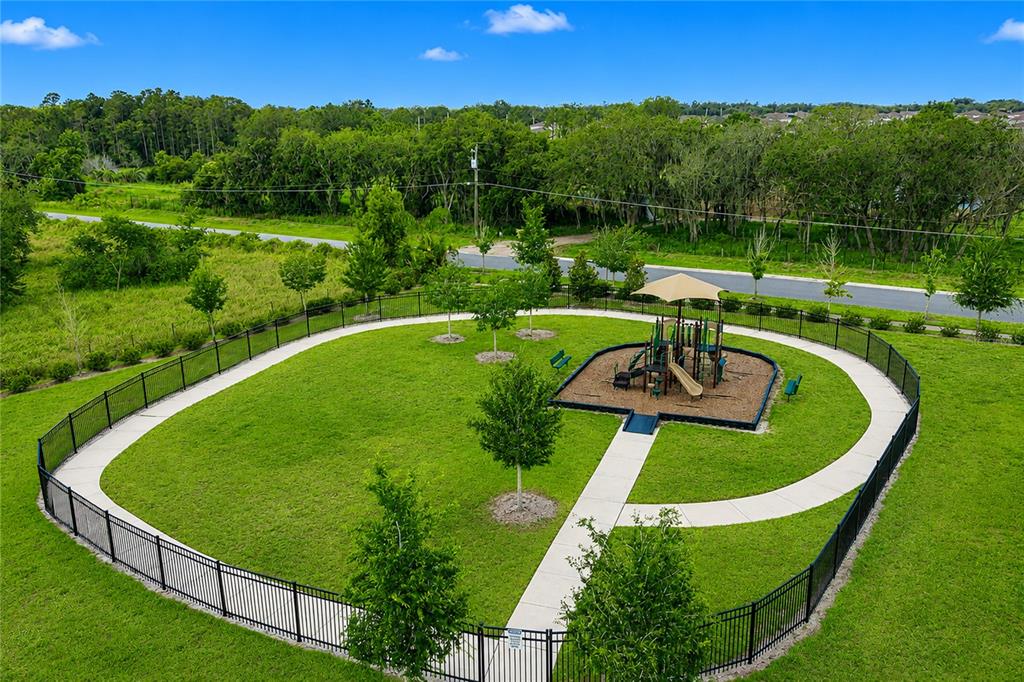 An aerial view shows a fenced playground with a slide, canopy, and walking path — 2824 SUNRIDGE LOOP, ST CLOUD, FL