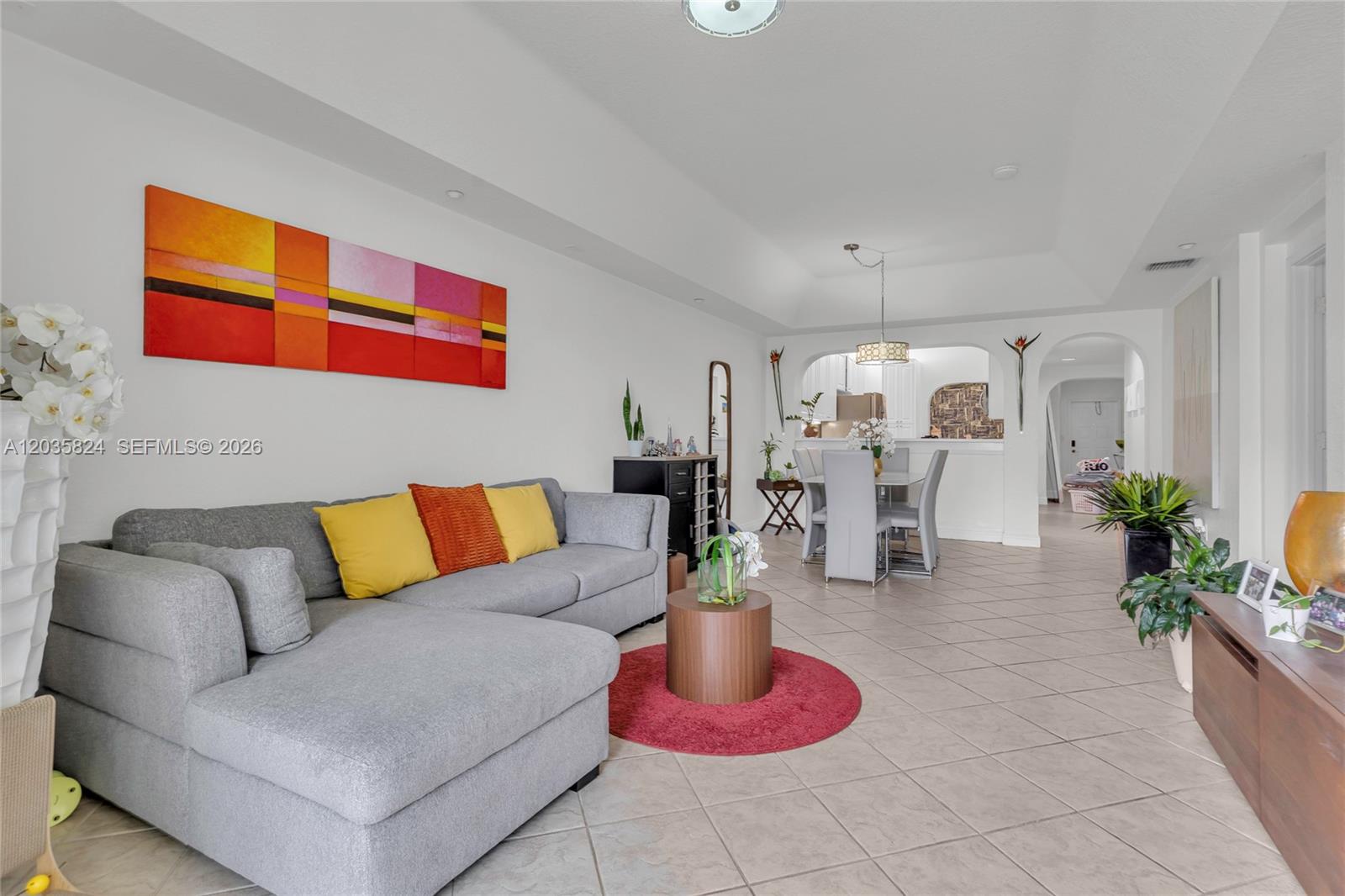 A living room with a gray sectional sofa, a red rug, and an adjacent dining area — 10710 NW 66th St # 104, Doral FL 33178, DORAL, FL