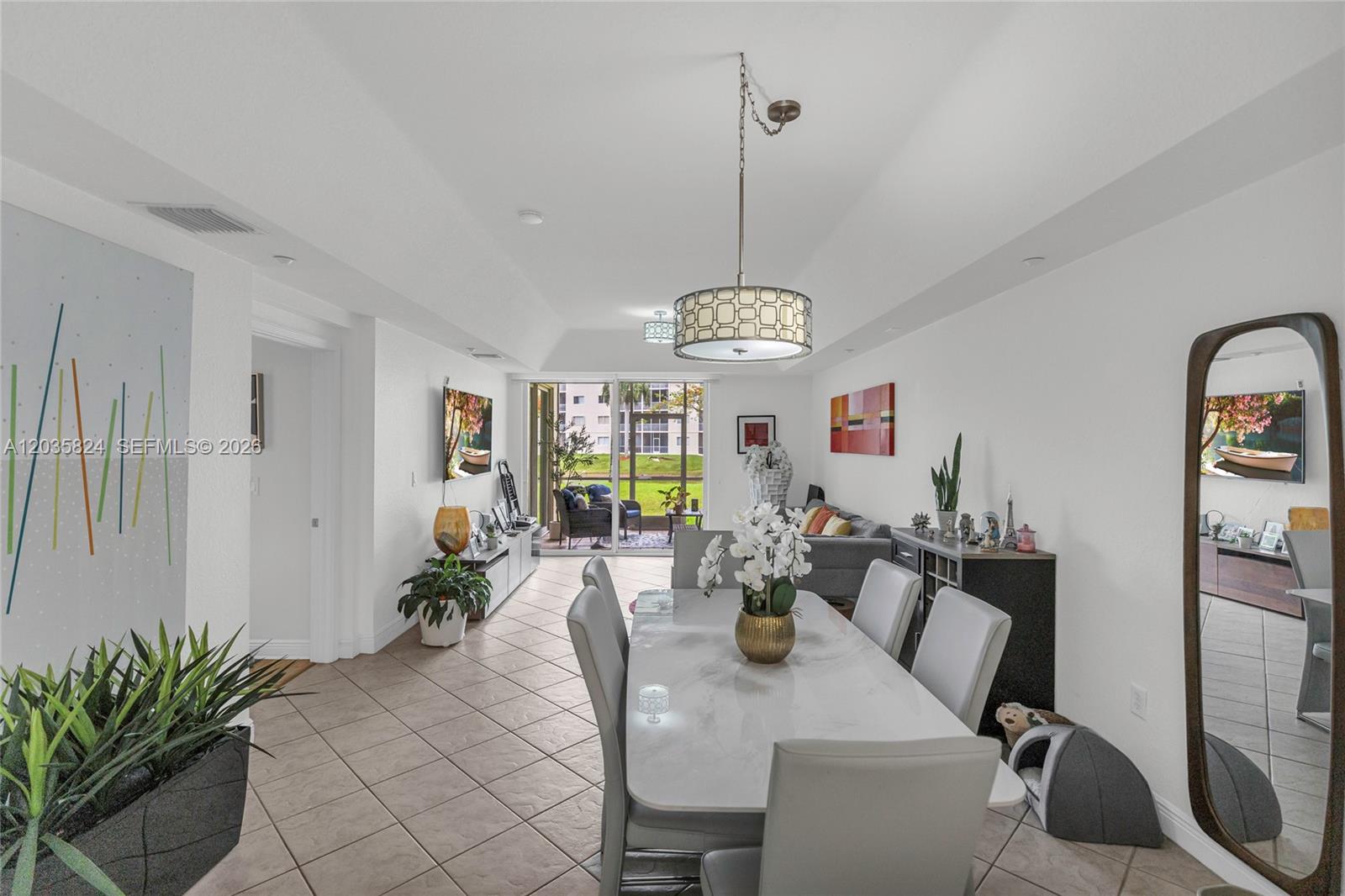 A dining area with a marble table and pendant light opens to a patio view — 10710 NW 66th St # 104, Doral FL 33178, DORAL, FL