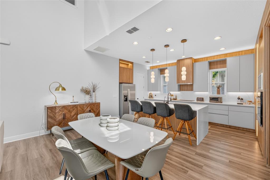 A modern kitchen and dining area feature light wood flooring, white cabinetry, and a kitchen island — 13660 CHAUVIN AVENUE, ORLANDO, FL