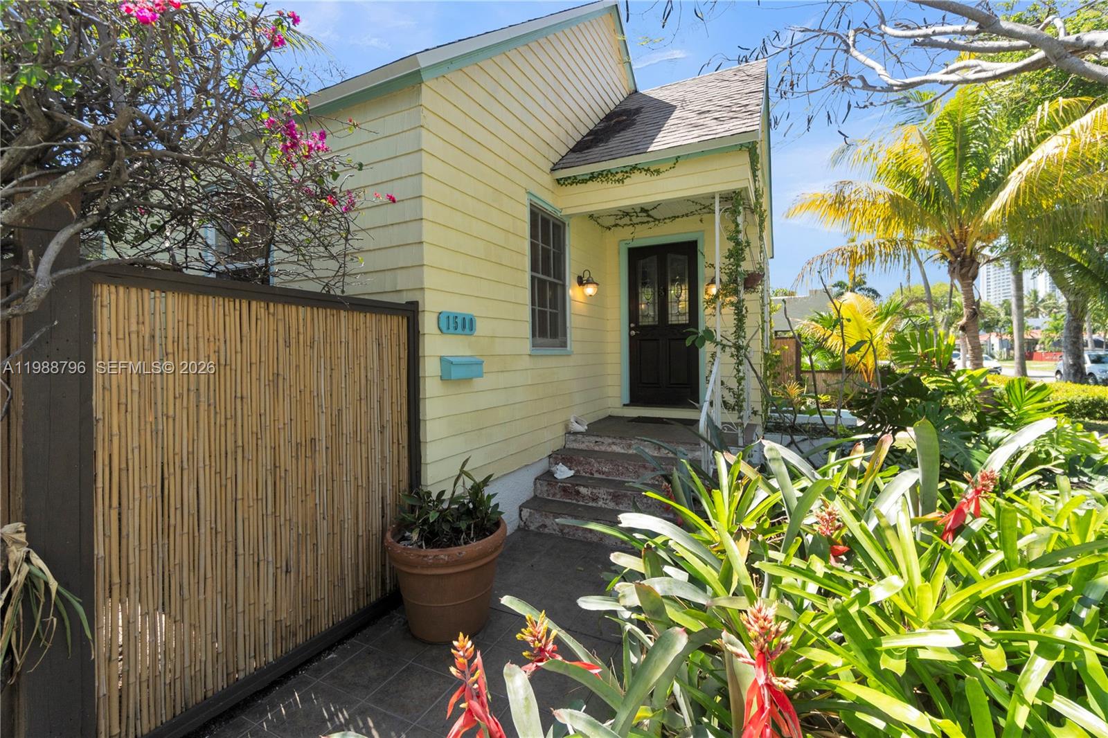 A yellow house with a bamboo fence, front steps, and tropical landscaping — 1500 Jackson St, Hollywood FL 33020, HOLLYWOOD, FL