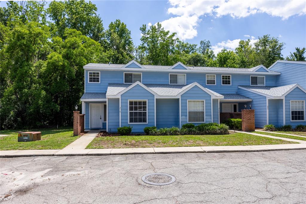 A blue two-story townhouse with a white front door and a small front yard — 218 NW 50TH BOULEVARD UNIT K, GAINESVILLE, FL