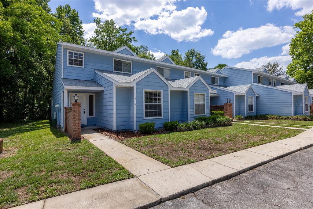 A row of light blue two-story townhomes with white trim and brick accents — 218 NW 50TH BOULEVARD UNIT K, GAINESVILLE, FL